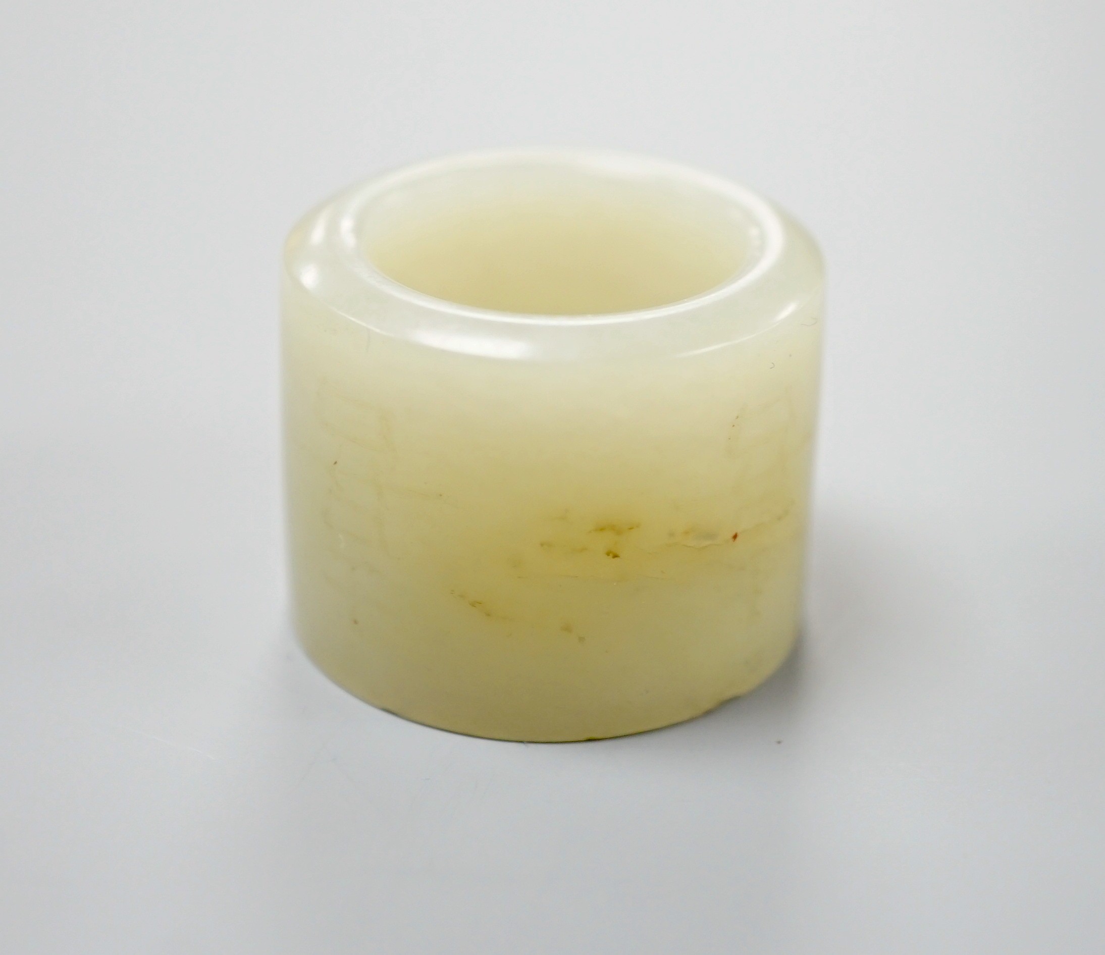 A 19th century Chinese pale celadon jade archer’s thumb ring, inscribed, 3 cm diameter